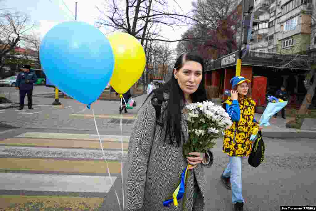 Женщина с букетом цветом и воздушными шарами подходит к памятнику Тараса Шевченко