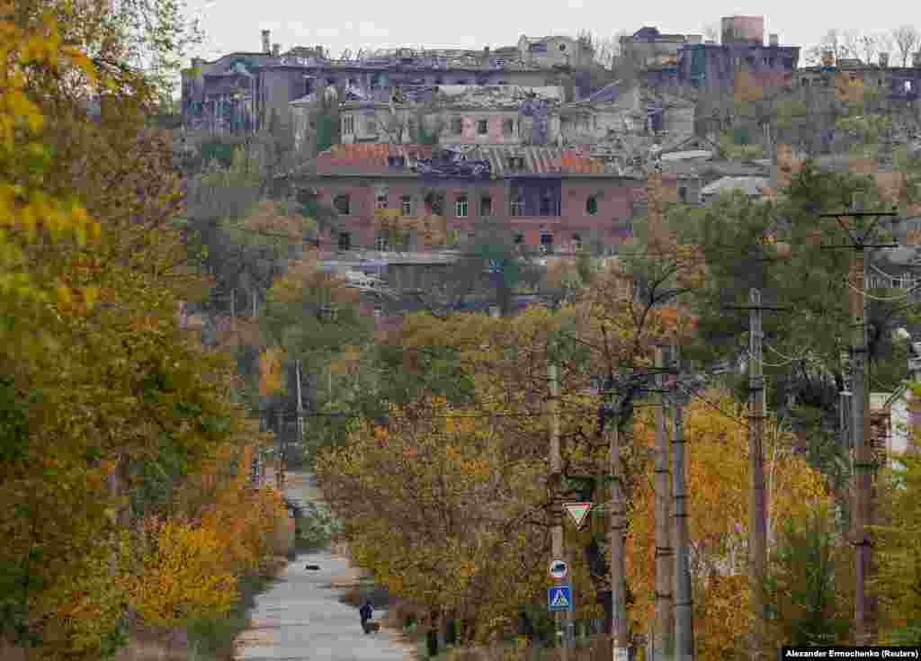 Мужчина толкает тележку в сторону разрушенного Мариуполя 29 октября 2022 года