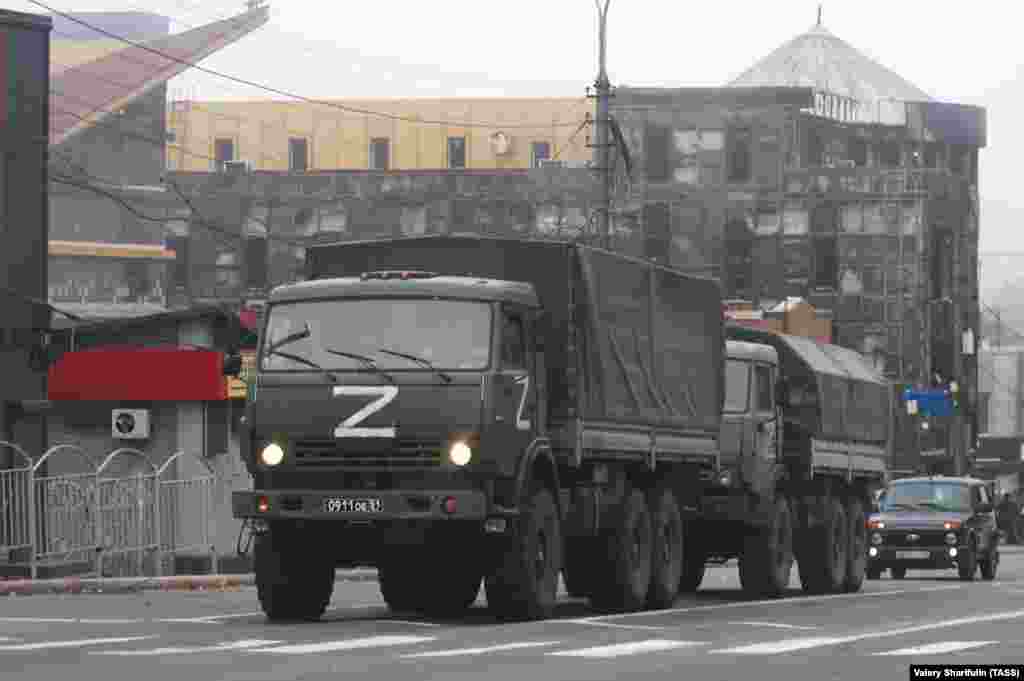 На фото, сделанном 19 октября, видны российские военные грузовики перед сильно поврежденным зданием в центре Мариуполя