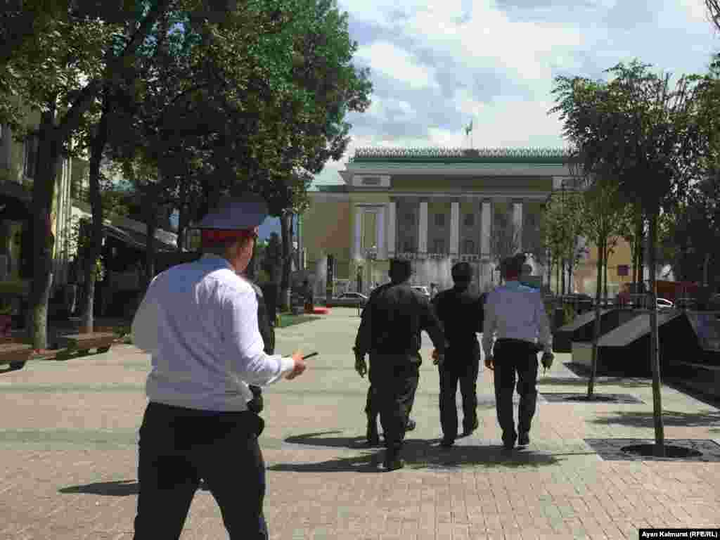 Полицейские ведут задержанного близ театра оперы и балета имени Абая.