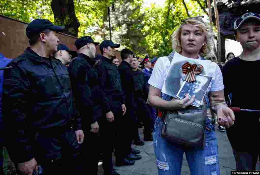 Помимо полиции в парке дежурило несколько десятков сотрудников спецназа. На фото: участница акции &laquo;Бессмертный полк&raquo; проходит мимо силовиков. Алматы, 9 мая 2019 года.