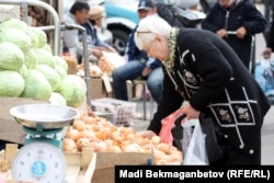 Женщина покупает овощи на рынке в Алматы.