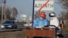 Kazakhstan - Officials wearing protective gear fill in documents at a checkpoint, set up to lock down the city to prevent the spread of coronavirus disease (COVID-19), on the outskirts of Almaty, Kazakhstan March 30, 2020. The sign reads "Almaty". REUTERS