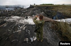 Пророссийский боевик фотографирует место крушения лайнера Boeing 777 авиакомпании Malaysia Airlines. Донецкая область, 17 июля 2014 года.