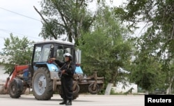 Полицейский блокирует улицу на месте спецоперации против подозреваемых боевиков. Актобе, 10 июня 2016 года.