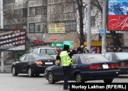 Инспектор дорожной полиции в Алматы регулирует транспортное движение.