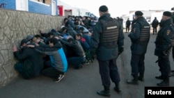 Russia -- Police detain migrant workers during a raid at a vegetable warehouse complex in the Biryulyovo district of Moscow, October 14, 2013